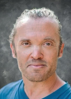 Man with curly blonde hair wearing a blue t-shirt