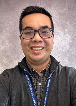 Man with short, black hair, wearing glasses and a black and gray checkered button up shirt